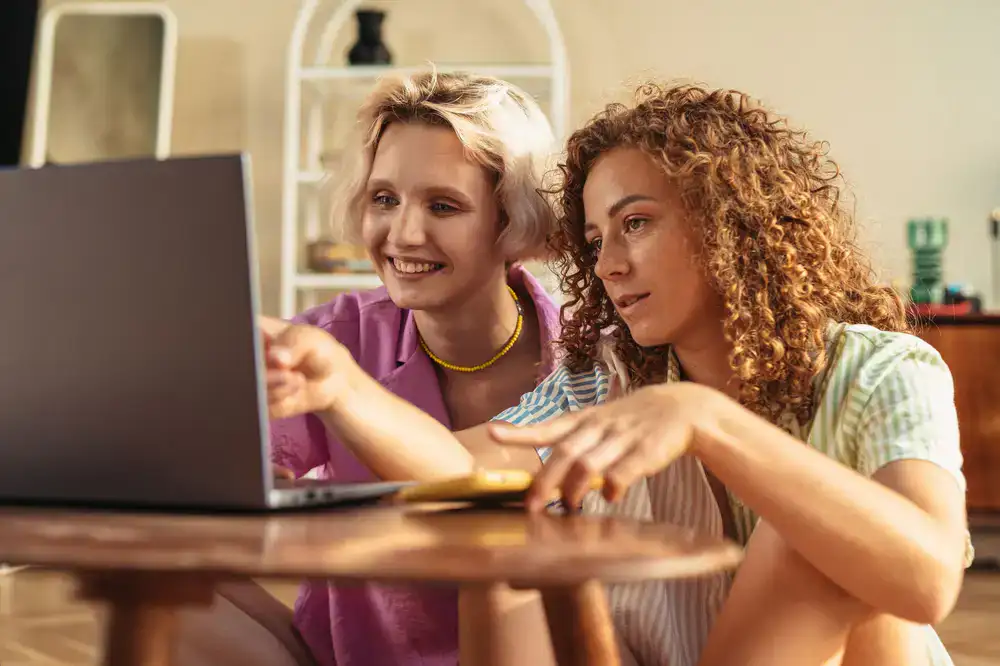 Two kids smiling while working on a laptop together