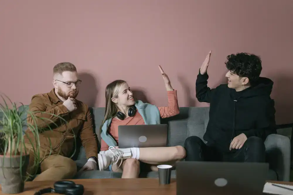 Two kids high-fiving over a laptop screen in a bright room